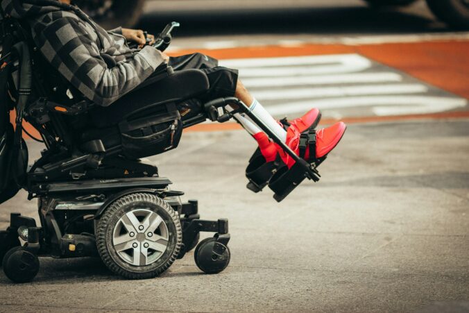 A photo of an electric wheelchair with someone in it, by a road.